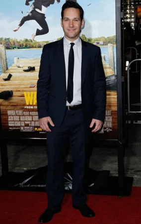 Actor Paul Rudd in a dark suit and tie standing on a red carpet in front of a movie poster in New York