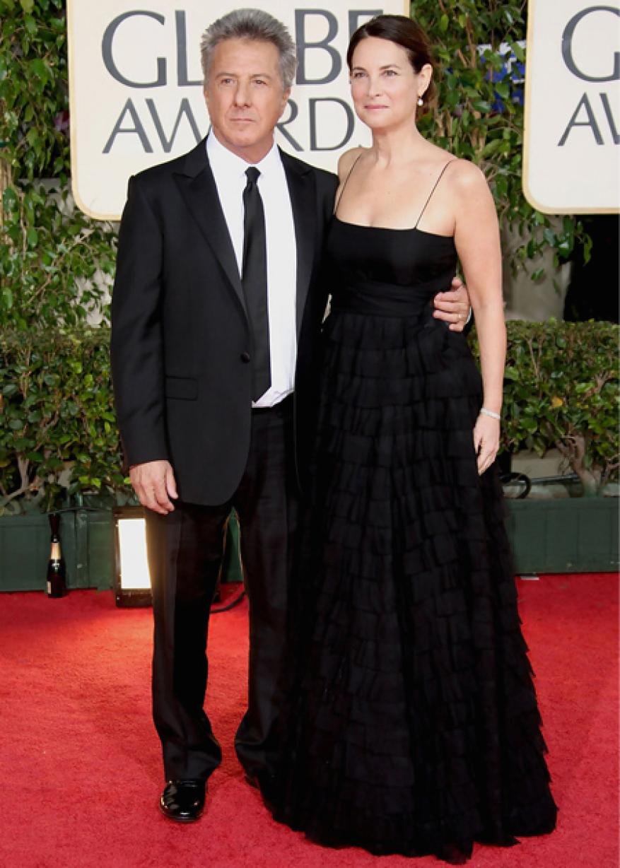 Dustin Hoffman and Lisa Gottsegen pose together on the red carpet in formal black attire at an awards event.