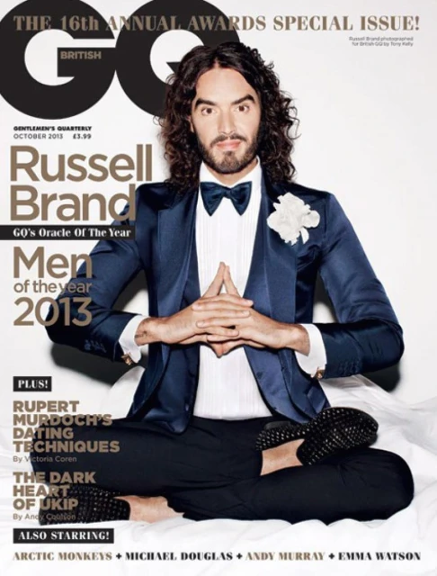 Magazine cover featuring Russell Brand in formalwear in a meditative pose, shot in a studio with neutral colors and magazine text elements.