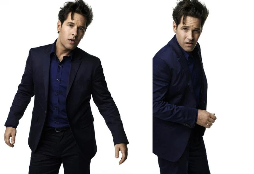 Studio portrait of Paul Rudd in a dark suit and blue shirt, posing against a white background with a duplicated image beside him.