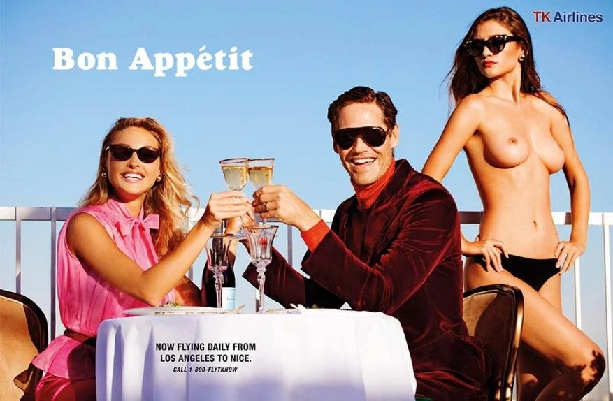 Three people at a table outdoors, drinking champagne, enjoying aperitifs, with a rooftop view and clear blue sky; airline advertising.