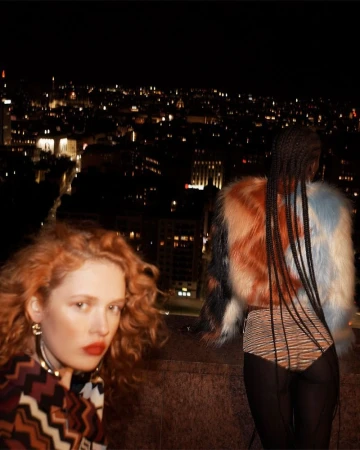 Two models on a rooftop at night with city lights in the background styled by Lorenzo Posocco in Milan.