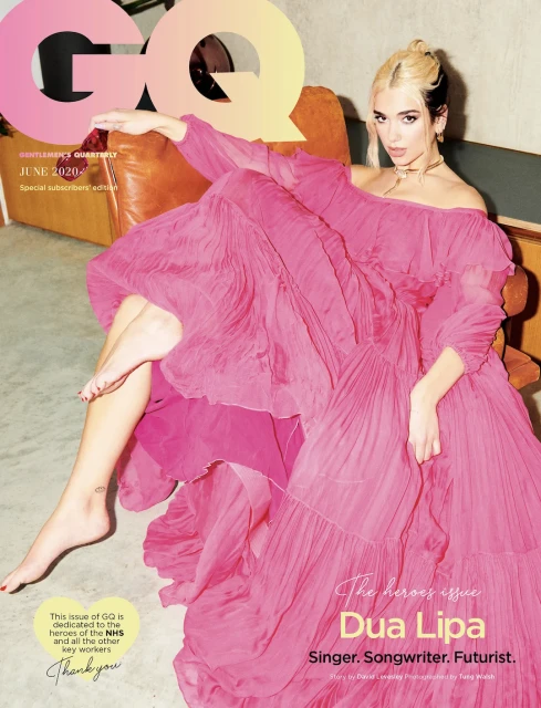 Dua Lipa graces a magazine cover in a flowing pink dress while seated in a chair against a neutral background, photographed in portrait.