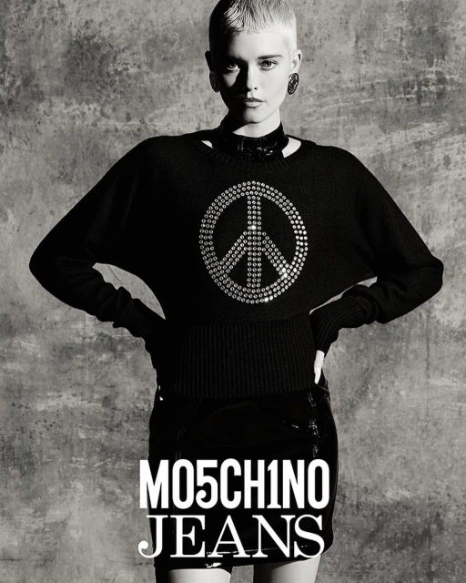 Black-and-white studio portrait of a young adult woman wearing a peace-symbol sweater and black mini skirt in a fashion shot.