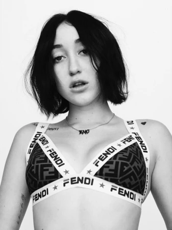 Portrait of Noah Cyrus wearing a branded Fendi bralette and a delicate necklace against a plain white background