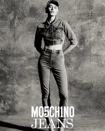 Model in denim jacket and high waisted jeans against a textured concrete background with bold white typography at the bottom.