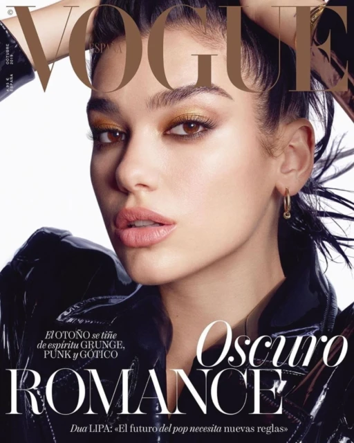 Vogue cover featuring a close-up portrait of a woman with bold gold eye makeup and a glossy black jacket, set against a white backdrop.