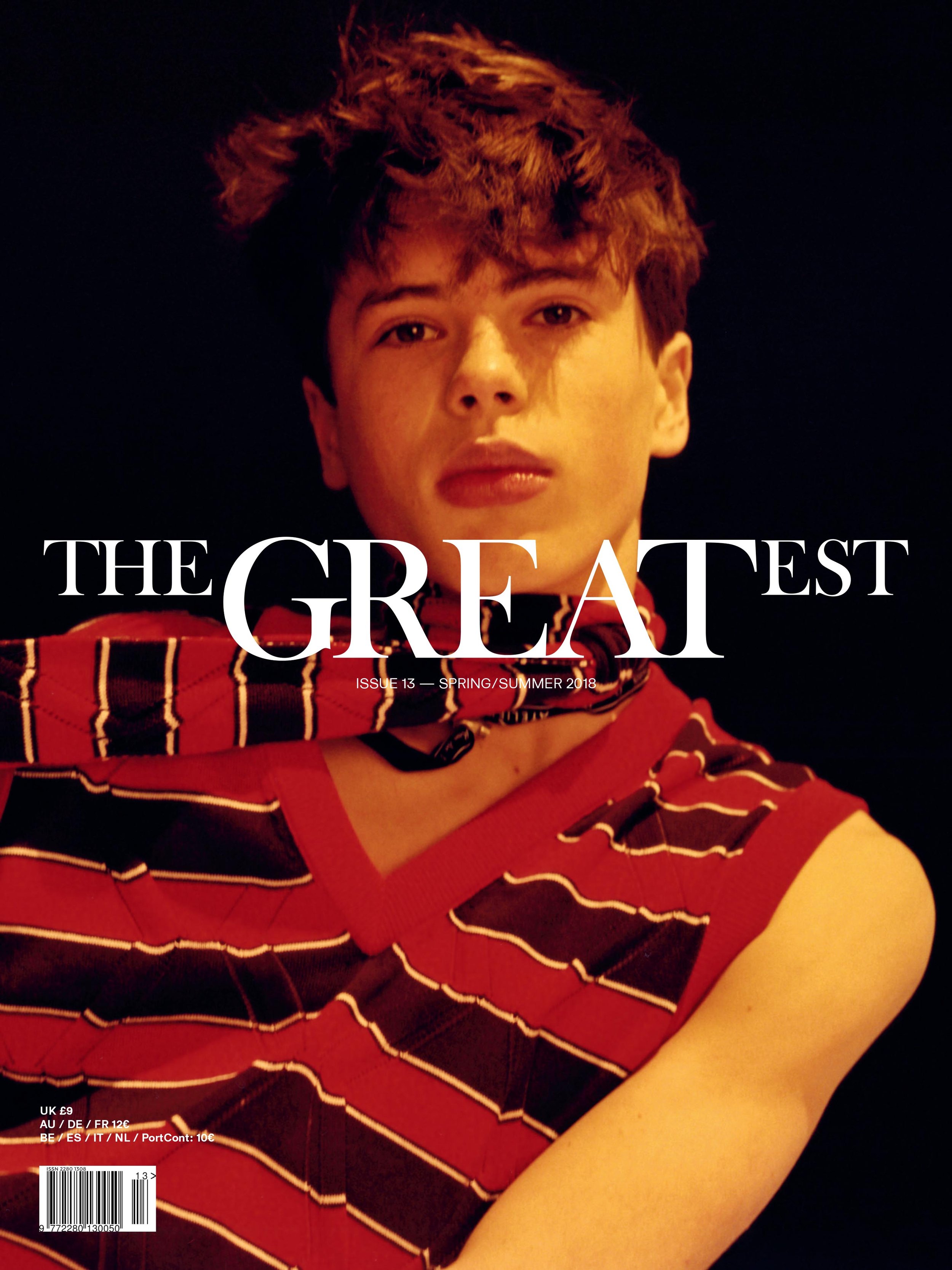 Magazine cover featuring a young male model with dark hair, wearing a striped top, set against a dark backdrop with bold white text.