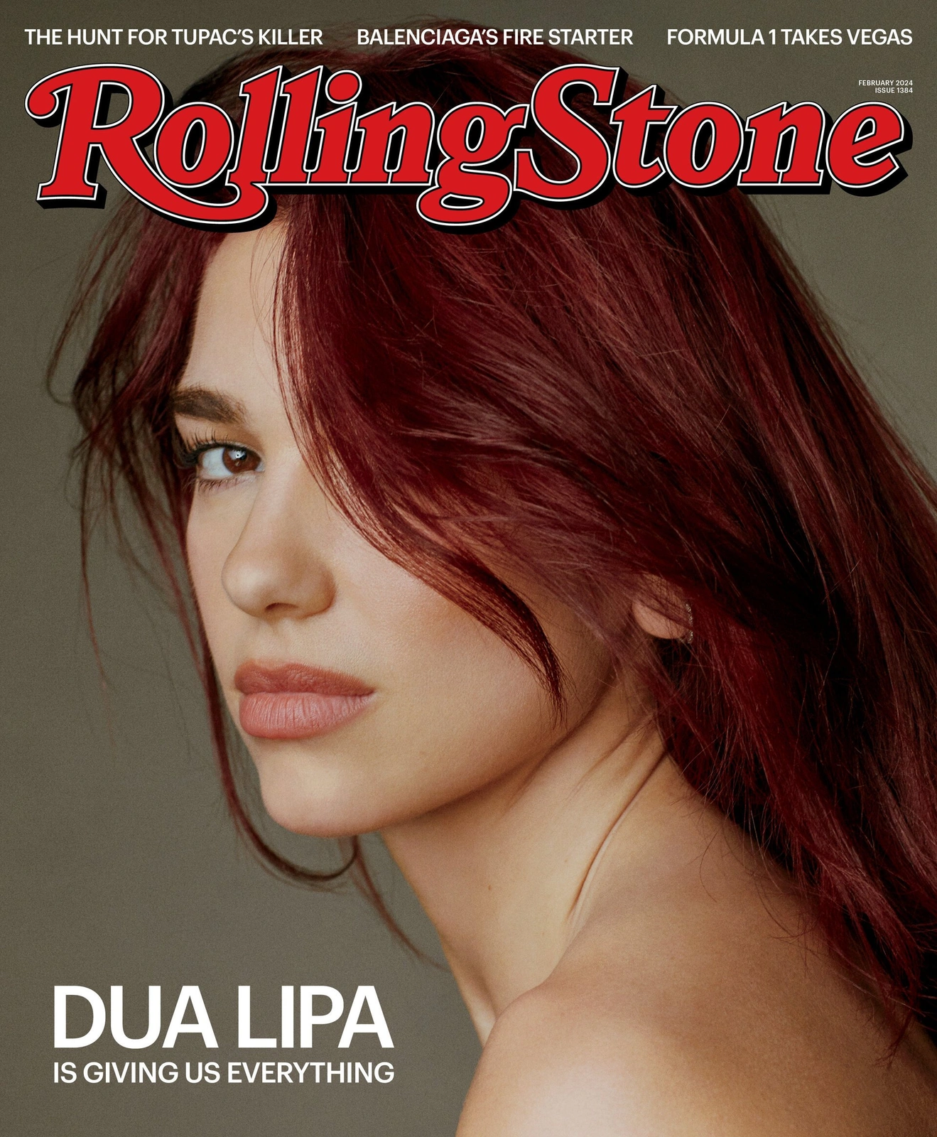 Close-up portrait of Dua Lipa with vibrant red hair against a plain dark grey studio background for a magazine cover