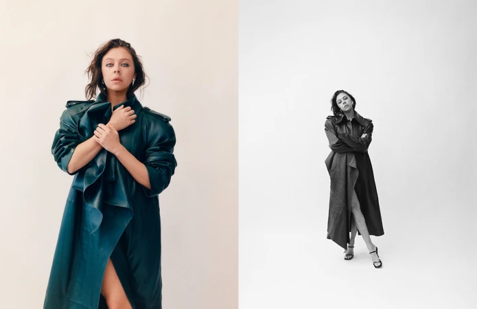 A woman in a dark teal leather trench coat standing against a white seamless background styled by Lucy Warren