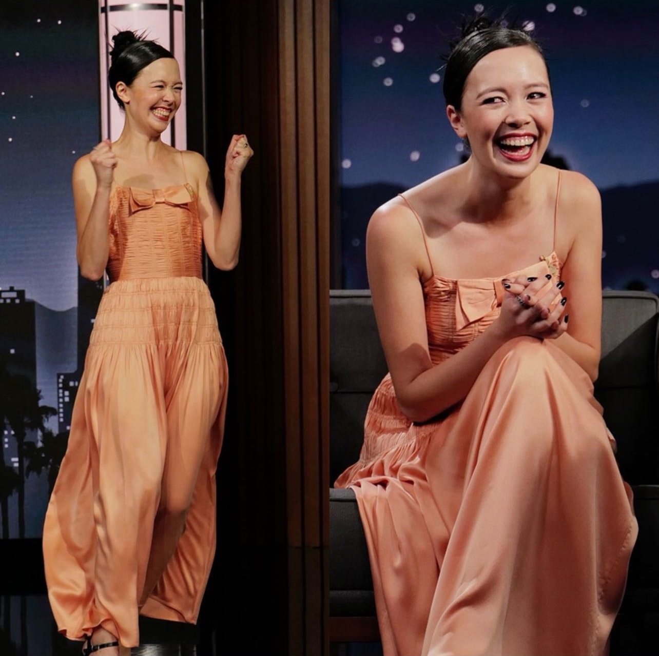 A woman with updo poses in a light orange dress on TV show set, smiling with hands clasped in front, captured in a medium shot.