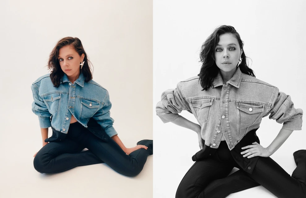 A woman poses in a light denim jacket and black pants, seated against a bright white backdrop, presented in both color and black and white.