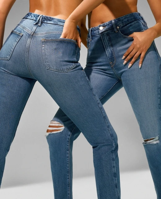 Two women pose indoors wearing blue jeans with distressed knees. The studio shot emphasizes fashion and denim textures.