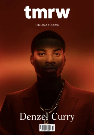 TMRW magazine cover featuring a portrait of Denzel Curry. The magazine has a red background with Denzel Curry wearing a red suit.