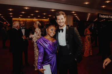 Quinta Brunson and Andrew Garfield smiling together at a formal evening event, captured by photographer Maggie Friedman.