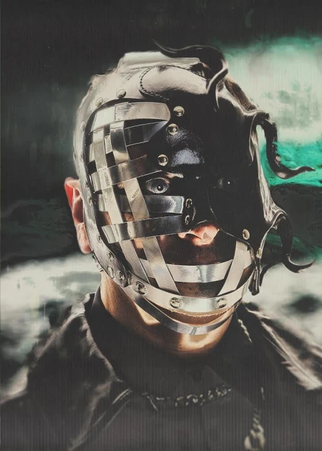 Person wearing elaborate metal and leather head covering with horn-like shapes against a dark, moody background with hints of teal.