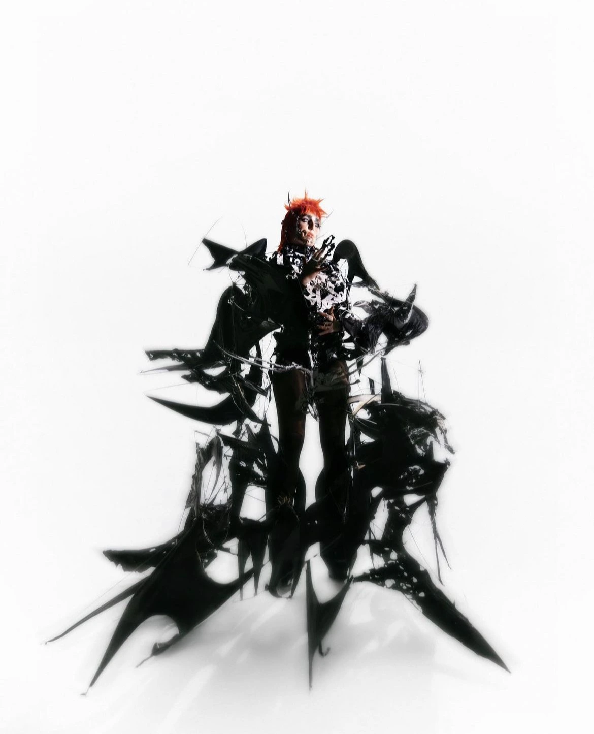 Model wearing avant-garde black sculptural garments against a stark white background by Maleeka Moss