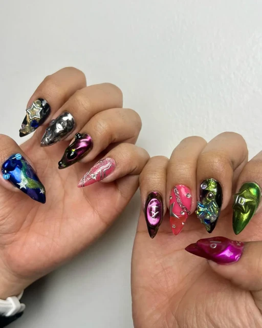 Close-up of hands showcasing artistic and colourful nail designs, including planets, stars, and metallic accents against a white background.