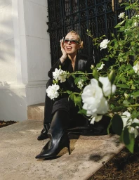 Woman in black blazer and boots posing outdoors with white roses in Los Angeles, nail art by Marielle Co