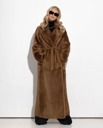 Model wearing dark sunglasses and a long brown belted coat against a plain white studio background.