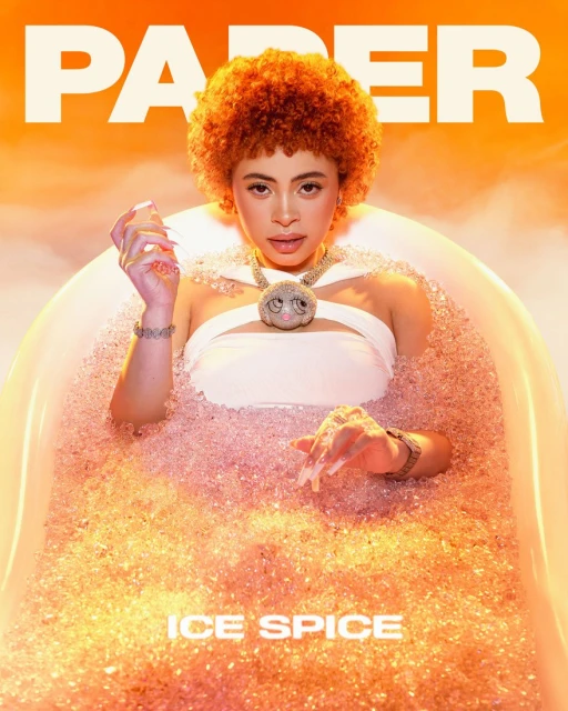 Ice Spice sits in a tub filled with crushed ice in front of an orange background with the text PAPER and ICE SPICE on it.