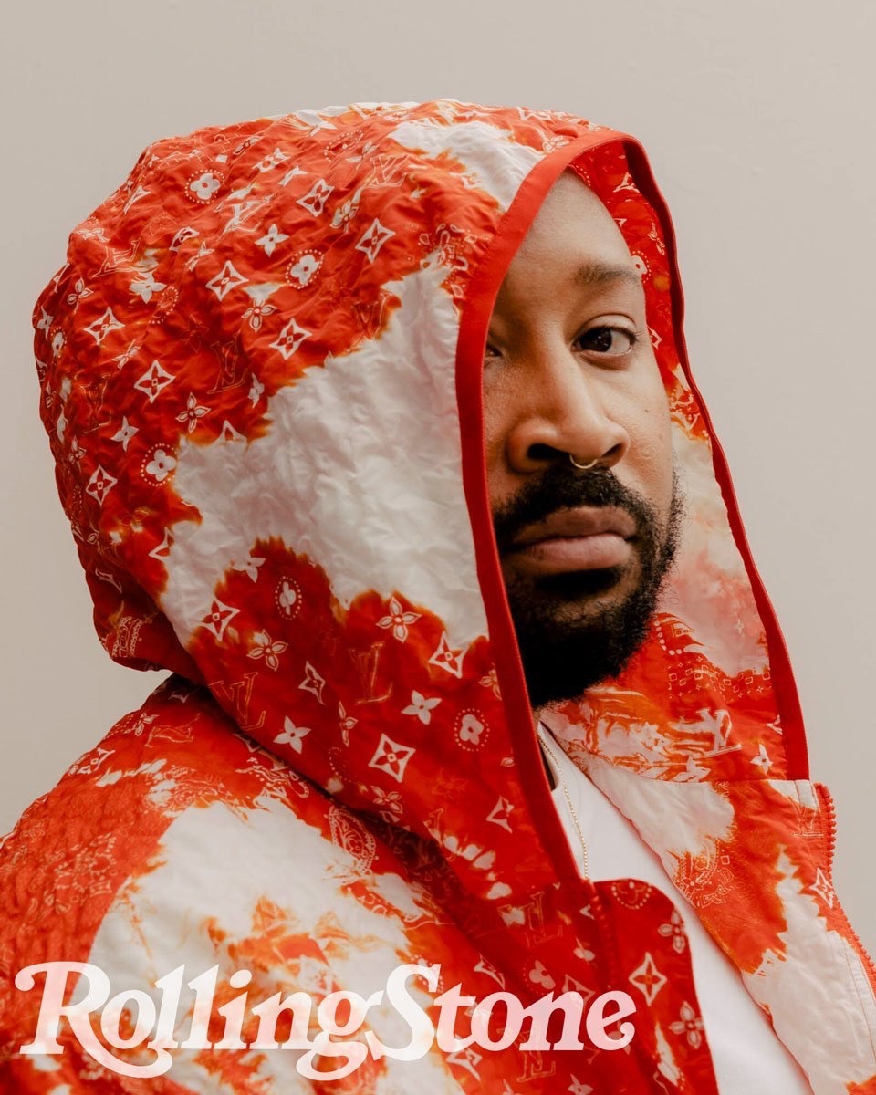 Portrait of a bearded adult male wearing a red and white patterned hooded jacket, with 'Rolling Stone' logo in the lower left corner.