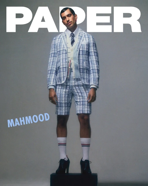 Magazine cover featuring a man in a plaid suit and heels, standing on a black cube, with 'PAPER' and 'MAHMOOD' text.
