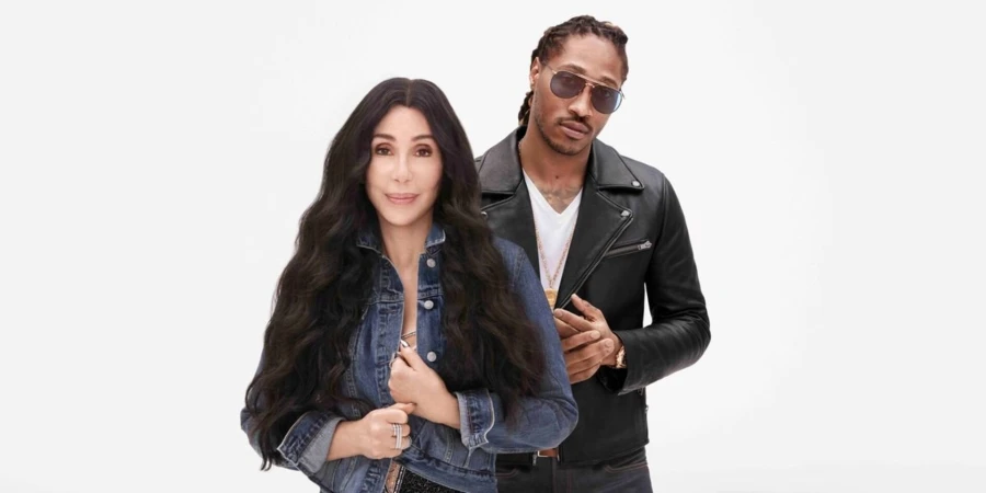 Cher and Future pose in a full shot in a bright photo studio. Cher wears a denim jacket and Future wears a black leather jacket.