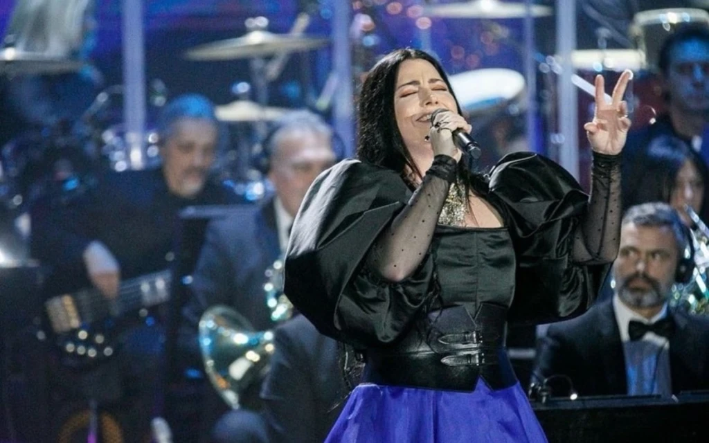 Vocalist Amy Lee of Evanescence performs live on stage in a black top and royal blue skirt in front of an orchestra.