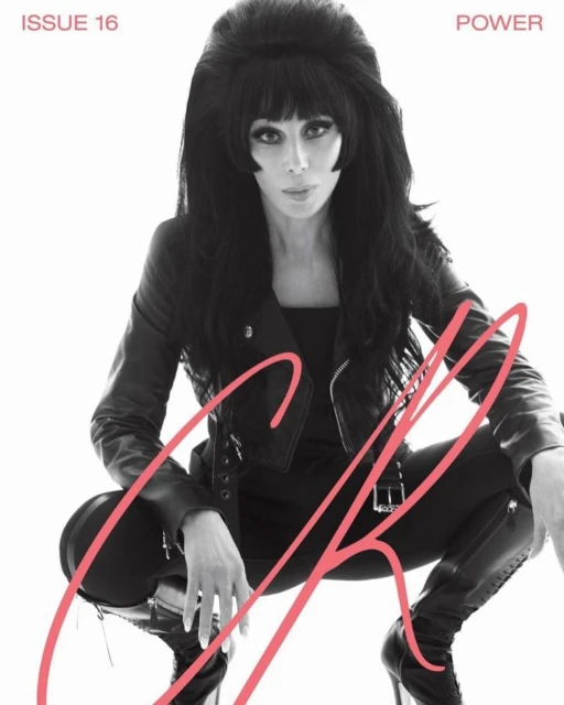 Cher poses in a black leather jacket and high heels on a magazine cover, featuring pink text, against a white background.