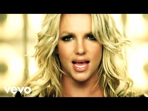 Close-up of a blonde woman singing with a bokeh background; the fair-skinned adult female faces the camera in a head and shoulders shot.