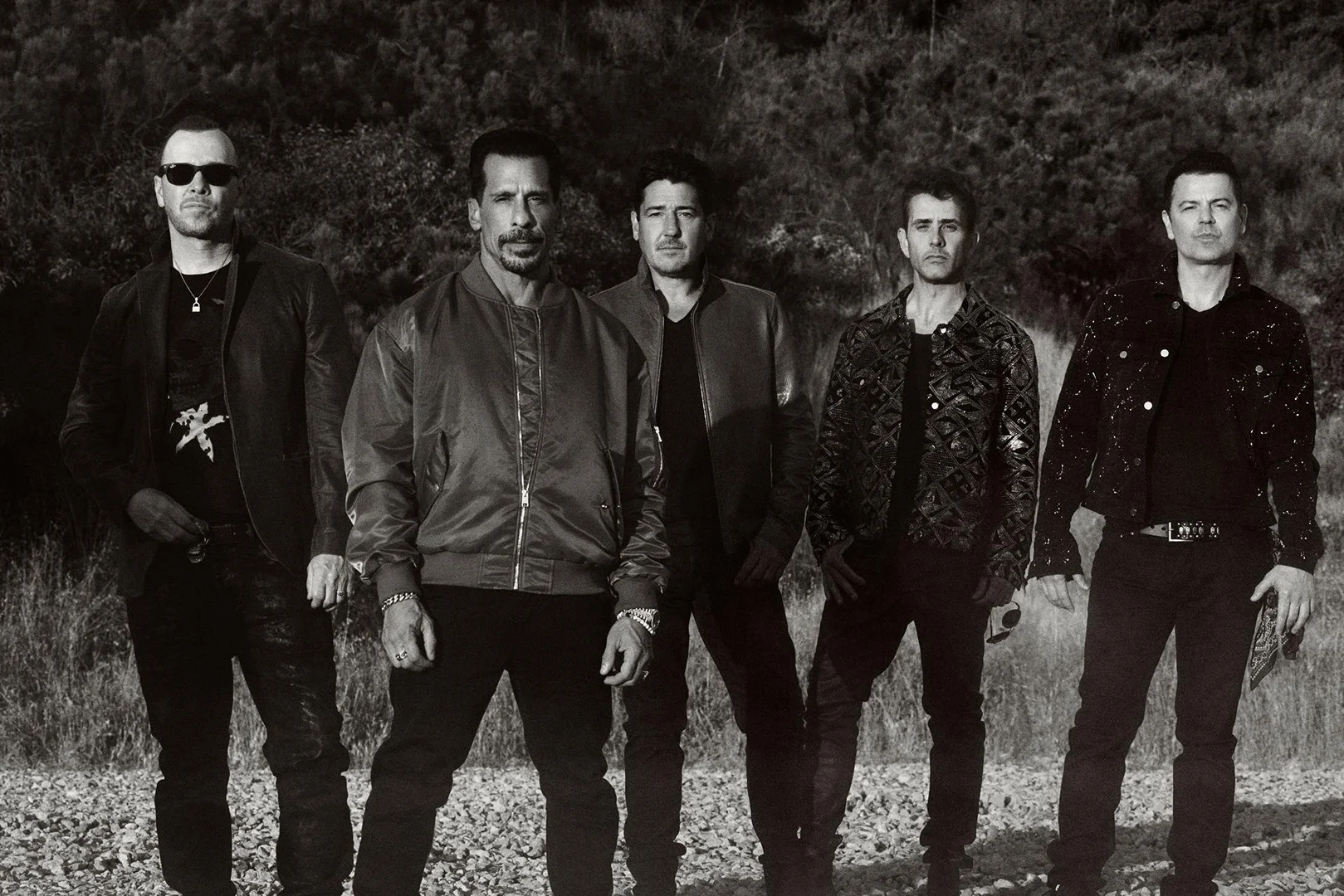 Monochrome portrait of five men standing outdoors in a rocky landscape styled by Marjan Malakpour