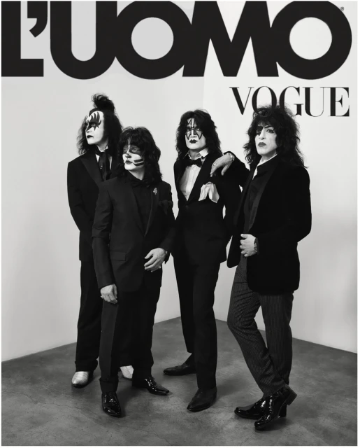 Four people in black suits with theatrical makeup pose in a studio, reminiscent of the rock band KISS, for L'Uomo Vogue.