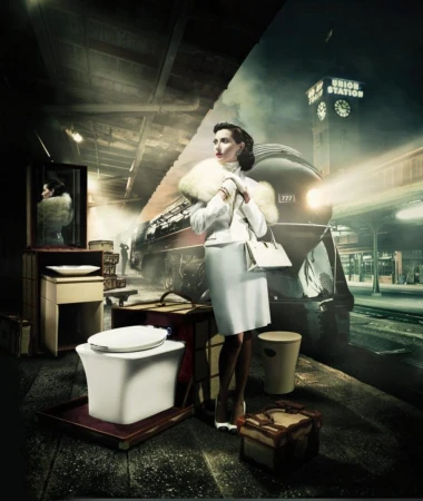Elegant woman in vintage attire stands near luggage on a train platform next to a modern toilet, with a train and station backdrop.