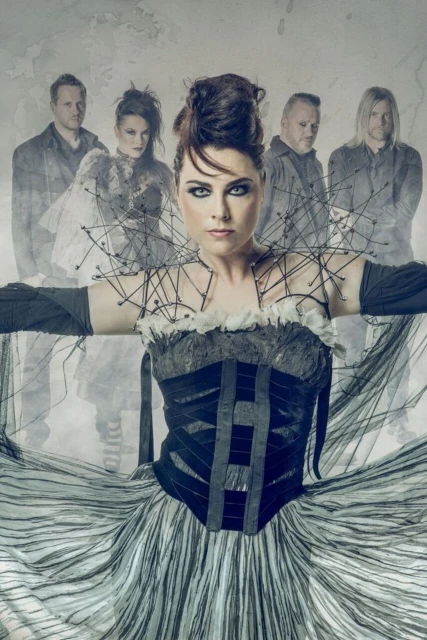 Band photo features a female lead singer in a striped dress, standing in front of the rest of the band in a grey indoor setting.