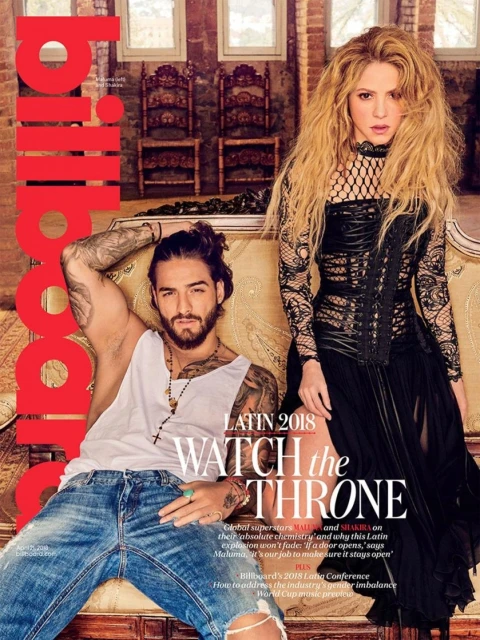 Billboard magazine cover featuring Maluma reclining and Shakira standing in a photo studio, with elegant furniture and large windows.
