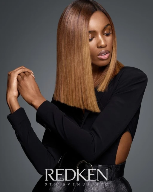 Elegant black woman in a black blazer with sleek blonde shoulder-length hair poses in a studio, showcasing a high-fashion look.