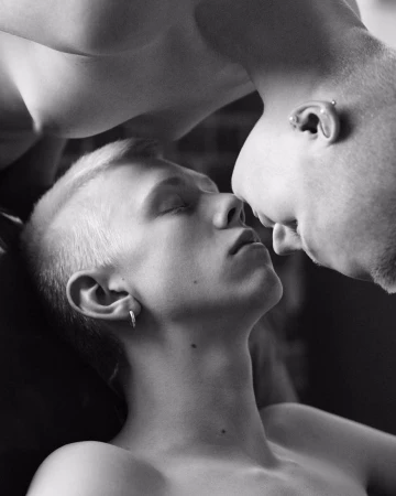 Close-up black and white portrait of two young men with close-cropped hair leaning close together face-to-face.