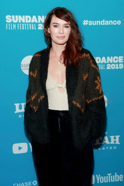 Woman with auburn hair wearing a black cardigan at the Sundance Film Festival stands in front of an event backdrop.