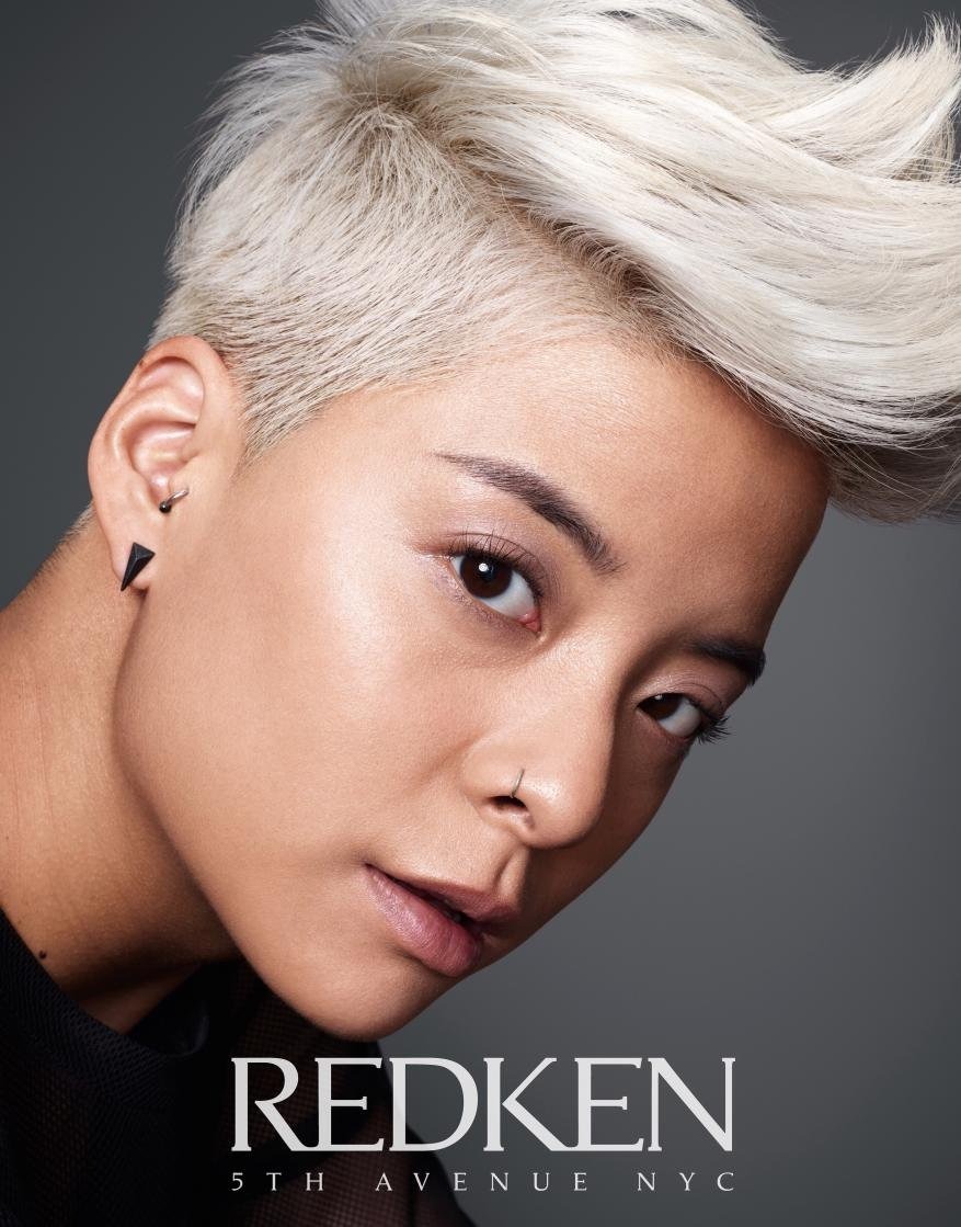 Close-up of a stylish adult female with platinum blonde pixie cut, wearing a nose ring and earrings. Shot in a photo studio.