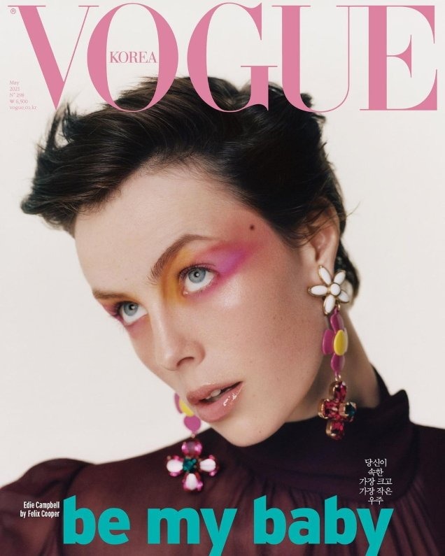Close-up of Edie Campbell on Vogue Korea cover, wearing colorful makeup, large floral earrings, with the magazine's masthead and text.