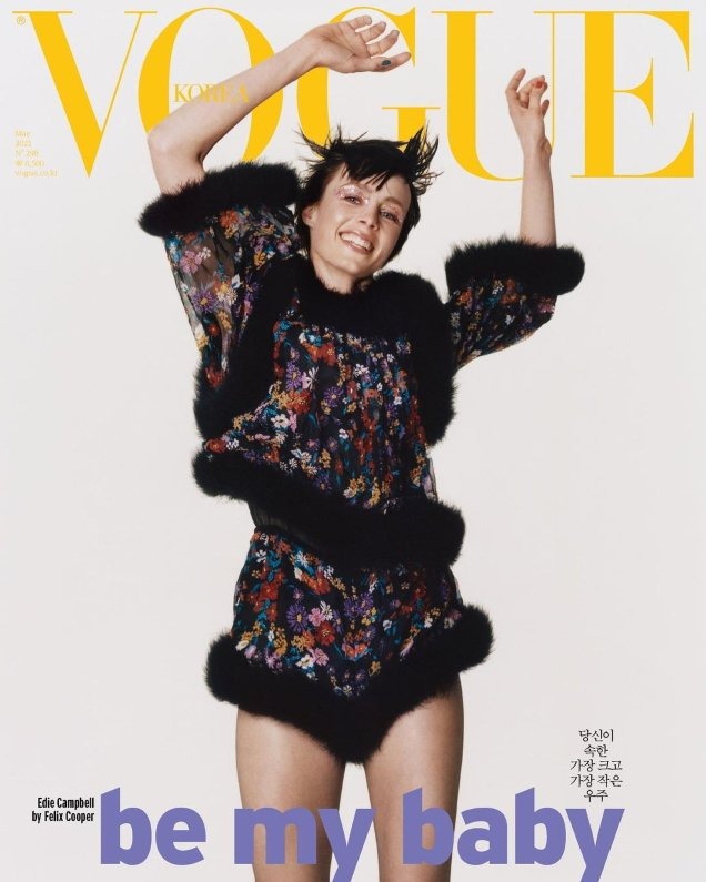 Vogue Korea cover featuring a woman with short dark hair, floral top and shorts with fur trim, smiling with hands raised in a studio shot.