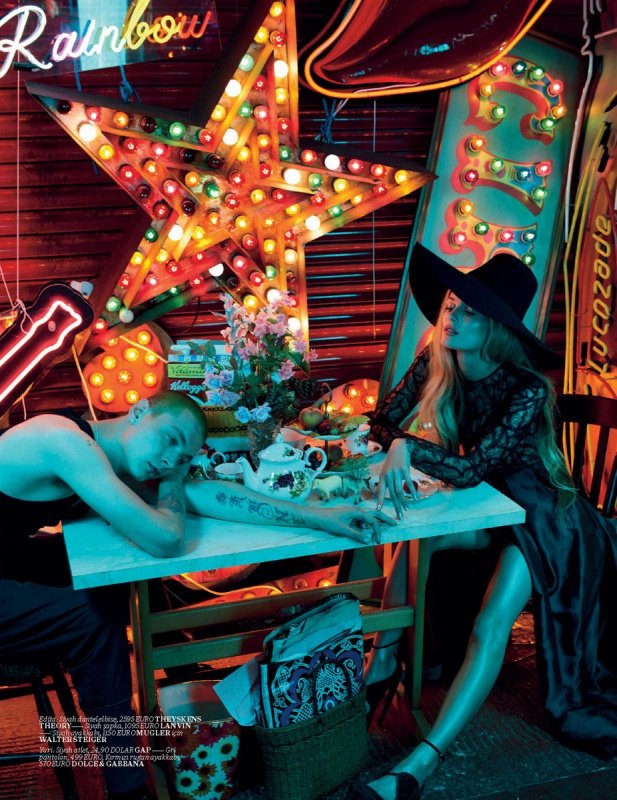 Fashion shot of a man and a woman at a tea party with neon lights, featuring a star-shaped light, hats, dark clothing, and tea set.