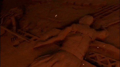 Digital painting of two people lying on an orange surface with rusted metal. Faint lights create a dark, eerie ambiance.