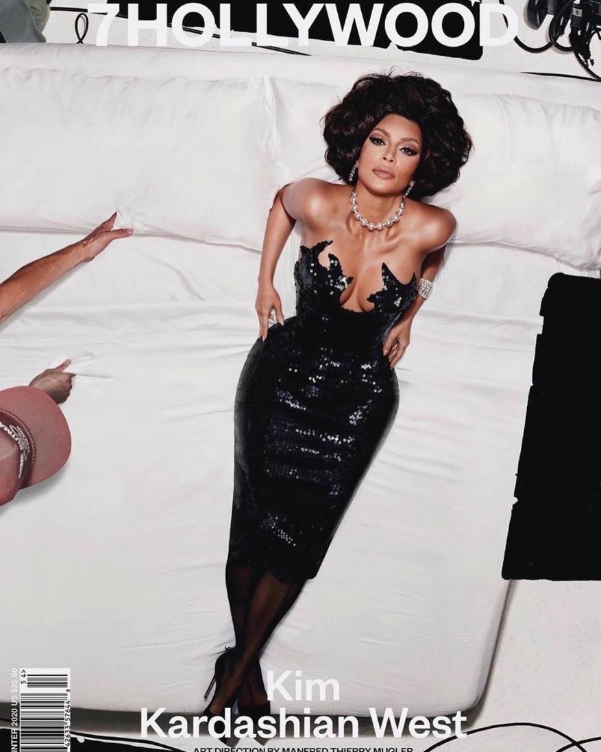 Kim Kardashian West poses on a white bed in a black sequin dress and high heels, featured on the cover of 7Hollywood magazine.