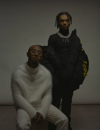 Two men posing against a neutral backdrop, styled by Mecca Cox in Los Angeles.