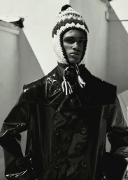 Black man wearing a glossy black jacket and patterned knitted winter hat styled by Mecca Cox
