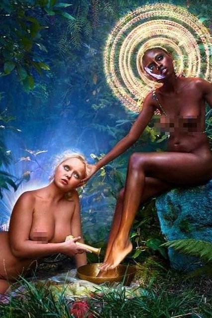 Two topless women, one with dark skin and the other with fair skin, are in a forest with magical lighting and a golden bowl.