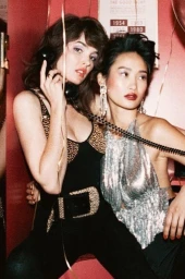 Two women holding a vintage telephone in a red room, styled with make-up by Melissa Rogers.