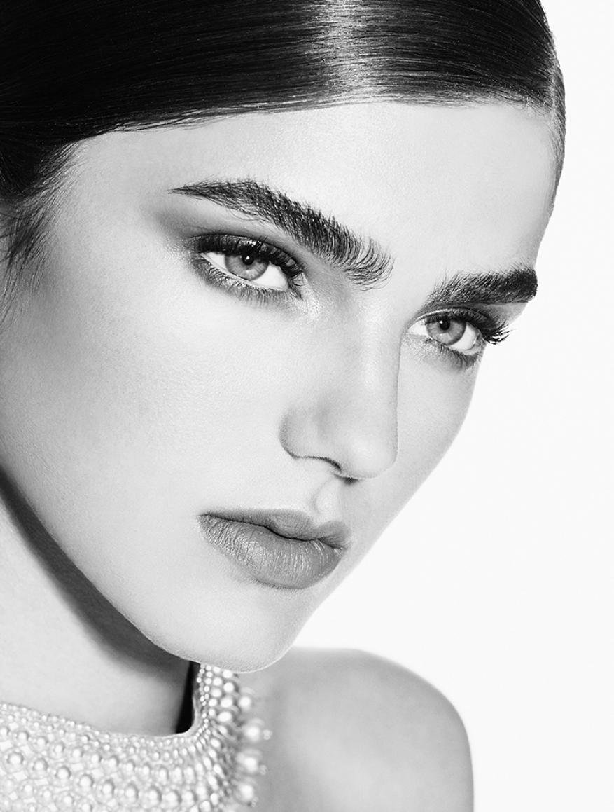 Striking black and white beauty portrait of an adult woman with pearls. Close-up shot of woman's face and shoulders on a white background.